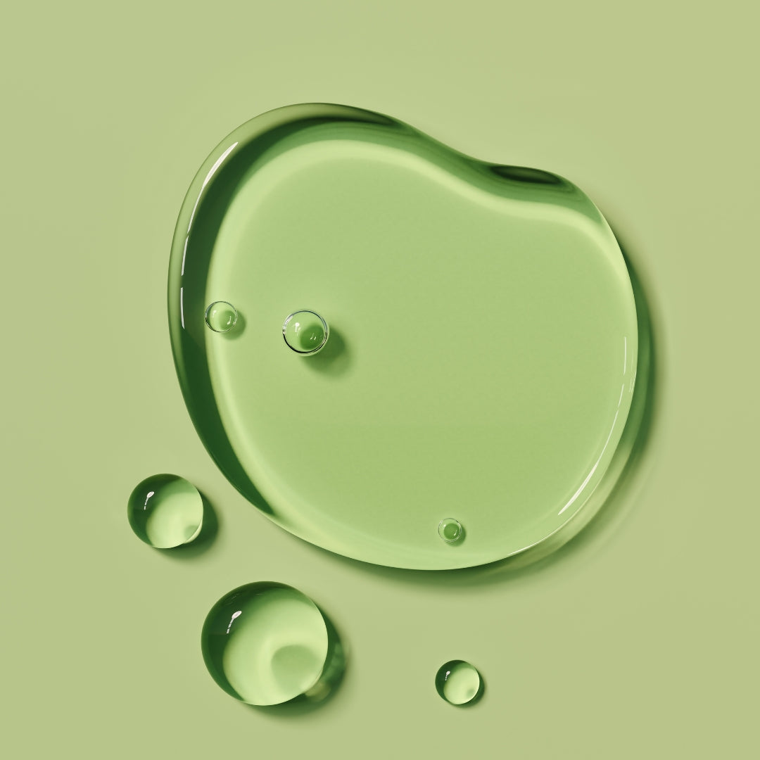 Closeup of clear liquid drops on a green background.