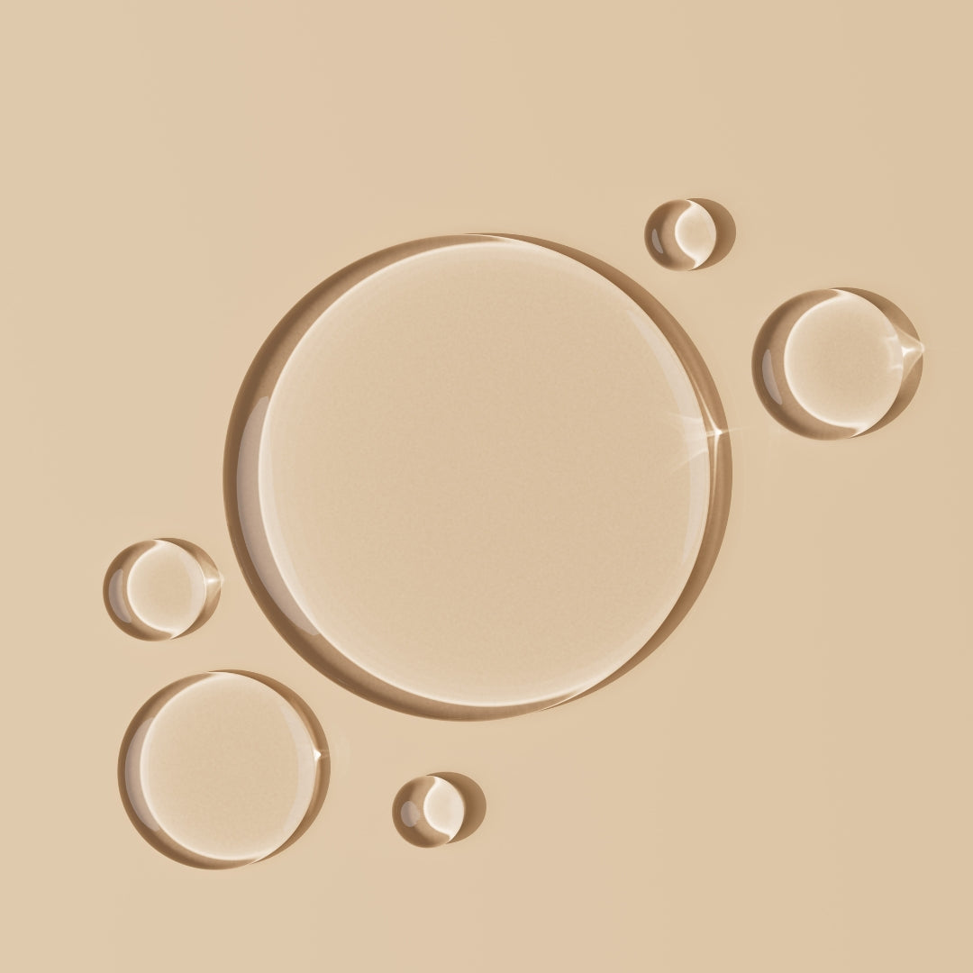 Closeup of clear liquid drops on a beige background.
